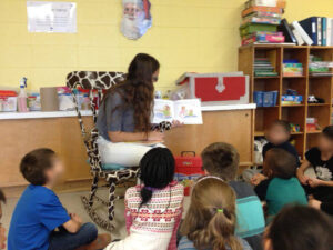 Une élève fait la lecture et des jeux avec des plus jeunes